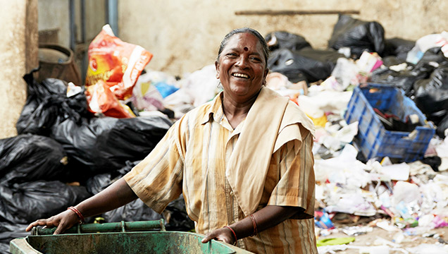 Smilende indisk kvinne plukker søppel