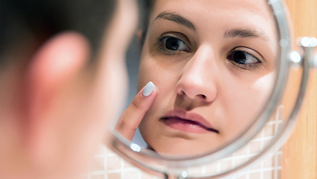 Kvinne studerer huden i ansiktet i et speil