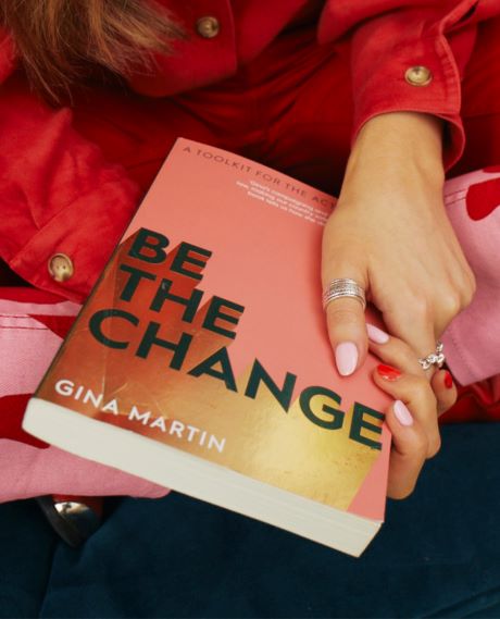 Kvinne holder en "Be The Change" bok av Gina Martin