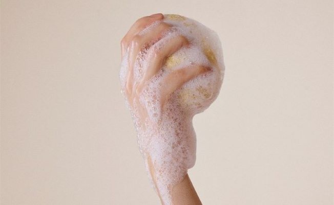 Hånd klemmer såpen ut av en svamp