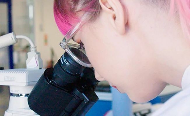 Kvinne titter ned i et mikroskop