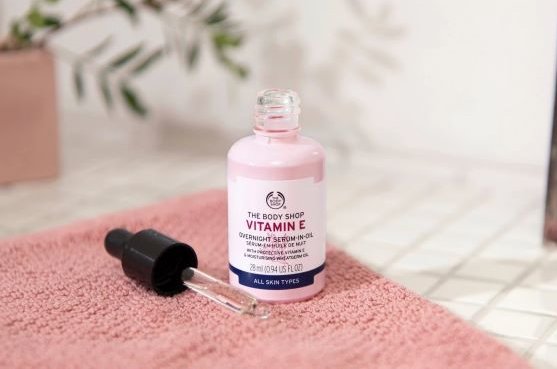 Vitamin E serum står på et rosa håndkle. Foto